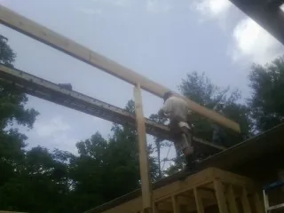 Carpenter setting a ridge beam over a new addition frame — Ice Dam Removal by Roofing Brothers in Ringling