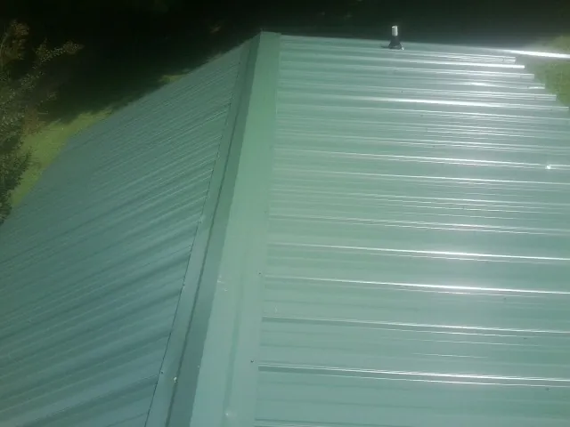 New green metal panels meeting at the ridge of a roof — Flat Roof Repair work by our crew in Ringling